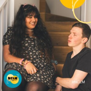 a young south asian girl waering a black dress sitting on stairs next to a young white boy in a navy t shirt